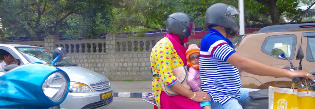 Child sandwiched between parents on scooter - she gave us a series of regal waves every time we overtook, or they did